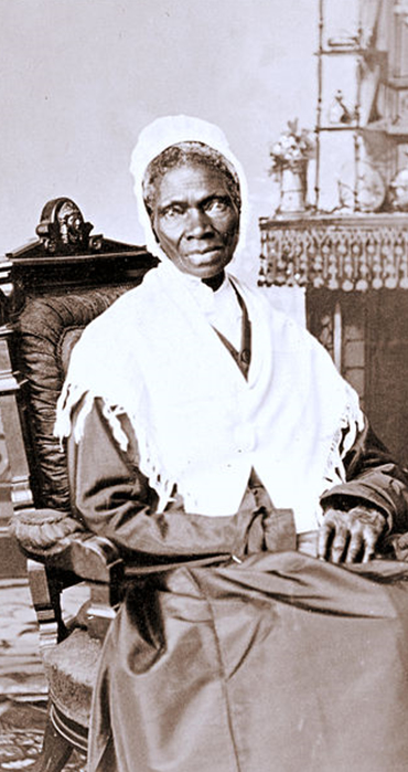 Schwarz-weiß Foto von Sojouner Truth. Sitzend mit Kleid, weißem Überhang und weißer Haube. Blick in die Kamera Schwarz-weiß Foto von Sojouner Truth. Sitzend mit Kleid, weißem Überhang und weißer Haube. Blick in die Kamera